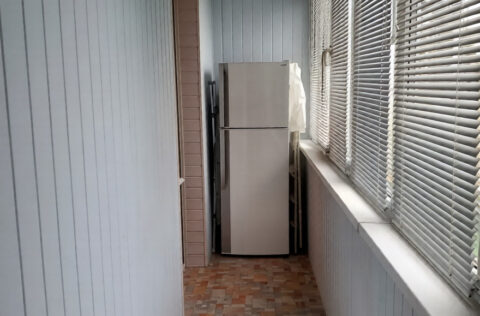 Enclosed balcony corridor with windows and storage space